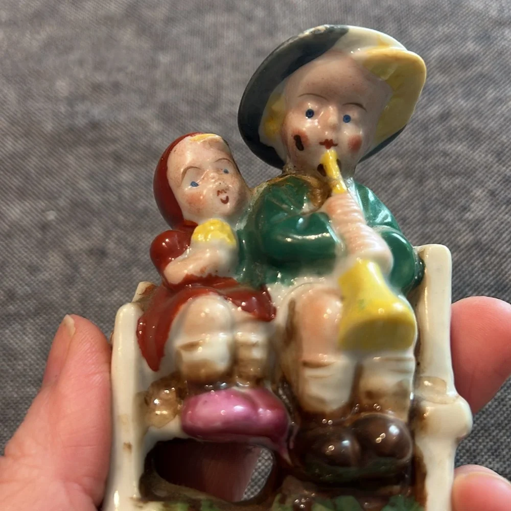Porcelain Girl and Boy sitting on a bench playing a horn-occupied Japan